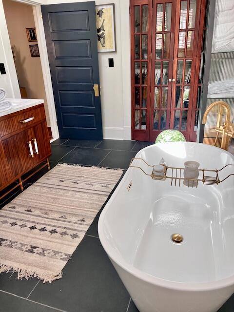 bathroom with baseboards, a freestanding bath, and tile patterned flooring