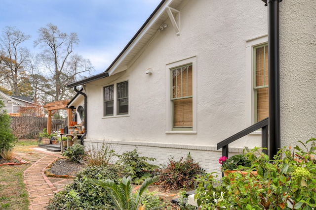 view of home's exterior featuring a patio area, fence, brick siding, and stucco siding