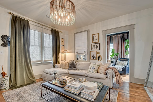 living room featuring baseboards, a notable chandelier, and wood finished floors