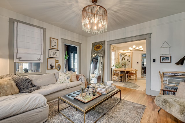 living room featuring light wood finished floors, a notable chandelier, and baseboards