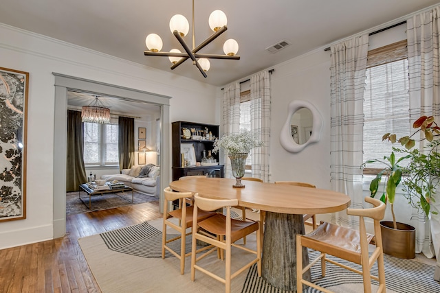 dining room with crown molding, a notable chandelier, baseboards, and wood-type flooring