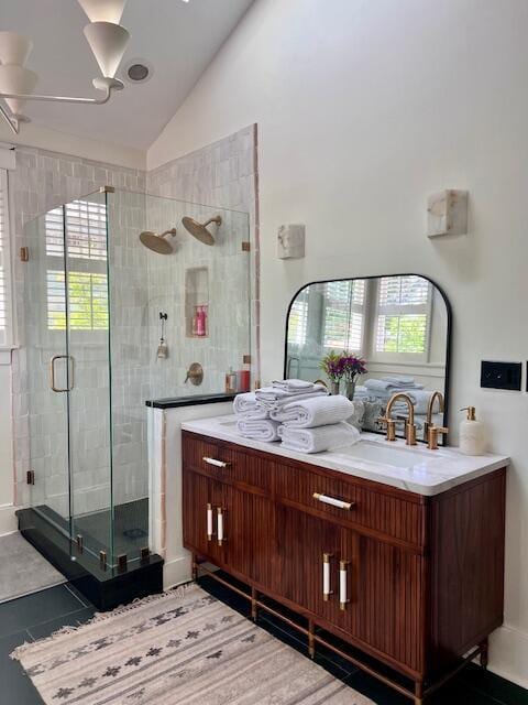 full bath with a sink, a shower stall, high vaulted ceiling, and double vanity