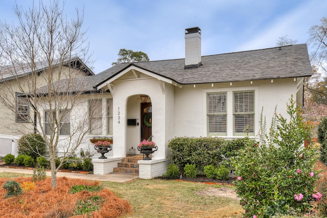 view of front of home featuring a chimney, stucco siding, a shingled roof, and a front lawn