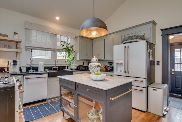 kitchen with light wood finished floors, a sink, gray cabinetry, white appliances, and open shelves