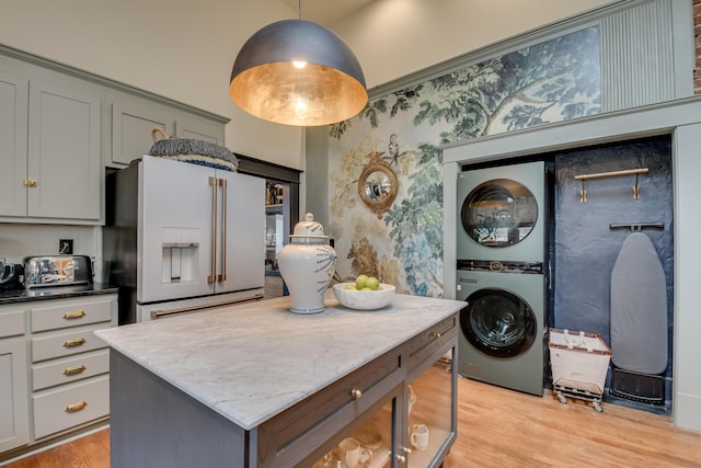 kitchen with light wood finished floors, stacked washer and dryer, high end white refrigerator, and wallpapered walls