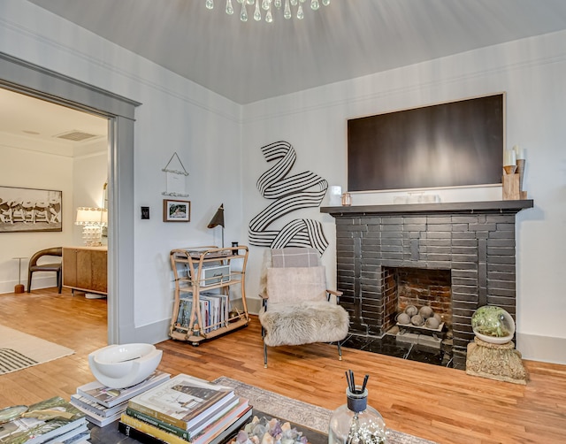 living area with visible vents, a brick fireplace, baseboards, and wood finished floors