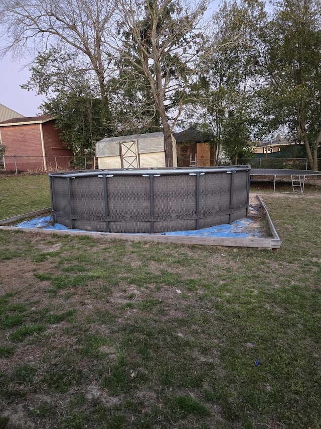 yard at dusk with a trampoline and an outdoor pool