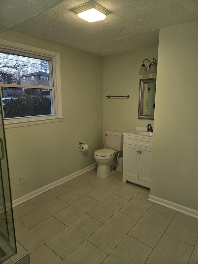 bathroom with a textured ceiling, vanity, toilet, and baseboards