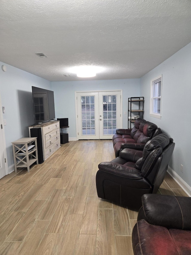 living area with visible vents, french doors, a textured ceiling, and light wood-style flooring