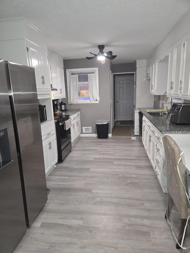 kitchen with white cabinetry, visible vents, and black appliances