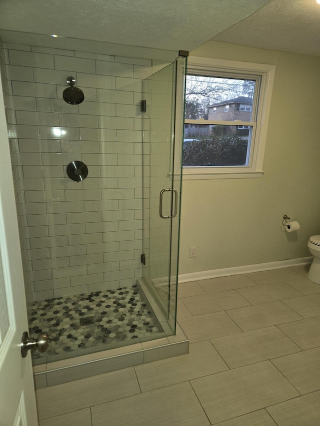 bathroom featuring toilet, a shower stall, and baseboards