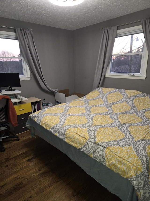 bedroom featuring dark wood-style flooring, multiple windows, and a textured ceiling