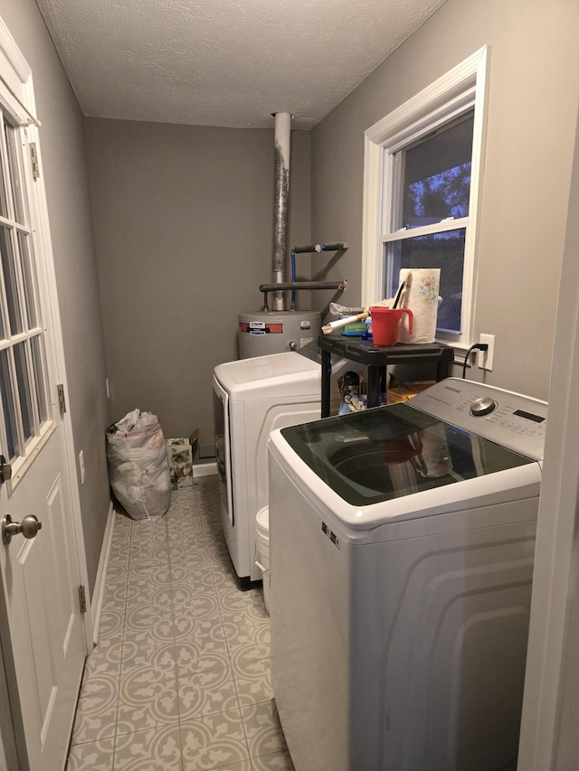 laundry area featuring a textured ceiling, laundry area, separate washer and dryer, and baseboards