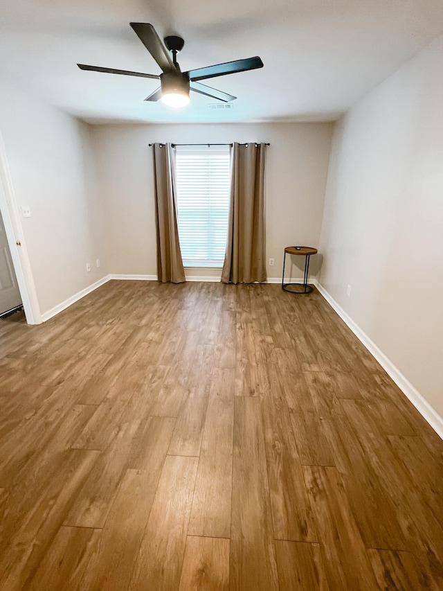spare room featuring wood finished floors, a ceiling fan, and baseboards