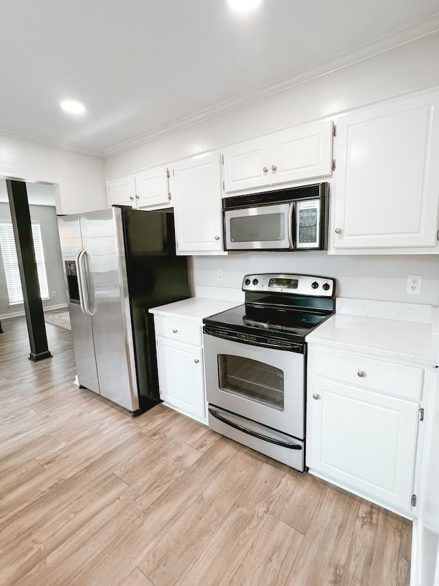 kitchen featuring white cabinets, stainless steel appliances, light wood-style flooring, light countertops, and ornamental molding