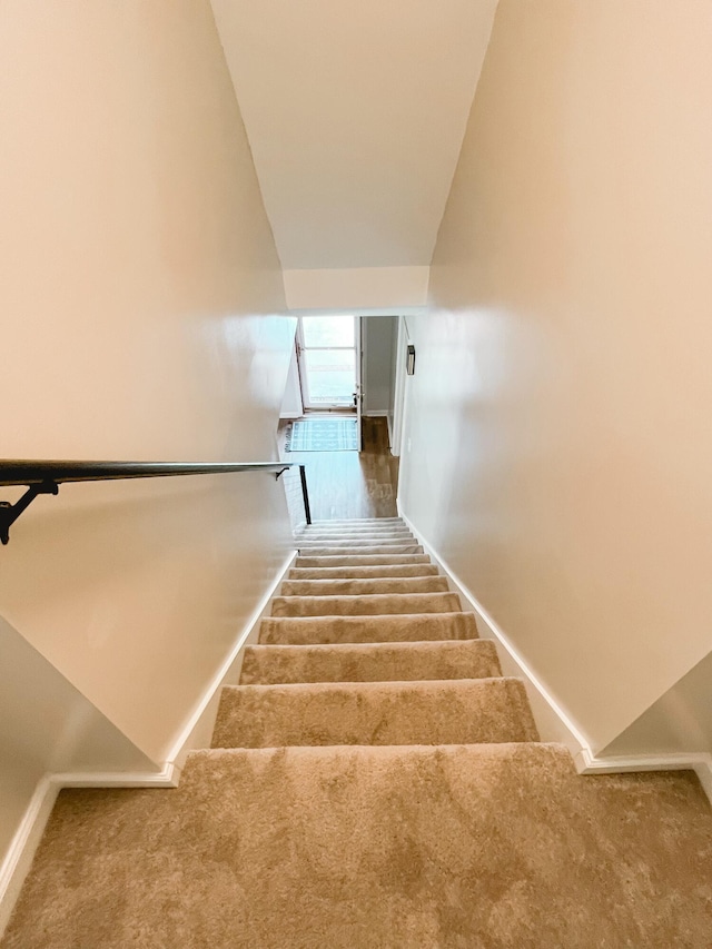 stairway featuring baseboards and carpet floors