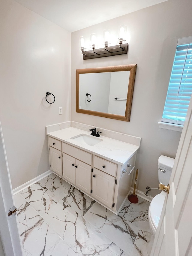 bathroom with marble finish floor, toilet, vanity, and baseboards