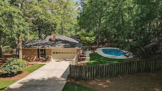 exterior space with a fenced in pool, a garage, and a front lawn