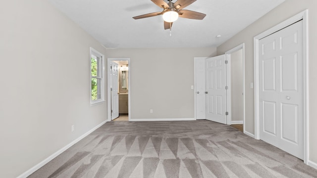 unfurnished bedroom with ensuite bathroom, ceiling fan, and light carpet