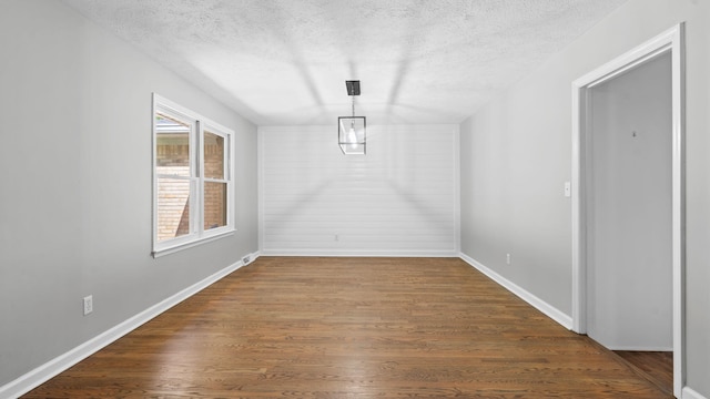 unfurnished dining area featuring dark hardwood / wood-style flooring and a textured ceiling