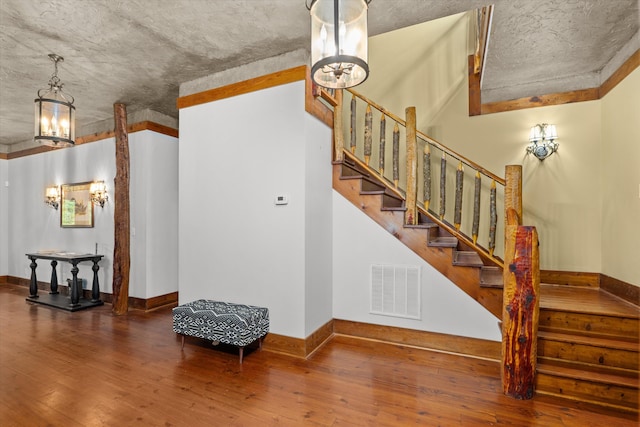 staircase with hardwood / wood-style flooring and an inviting chandelier