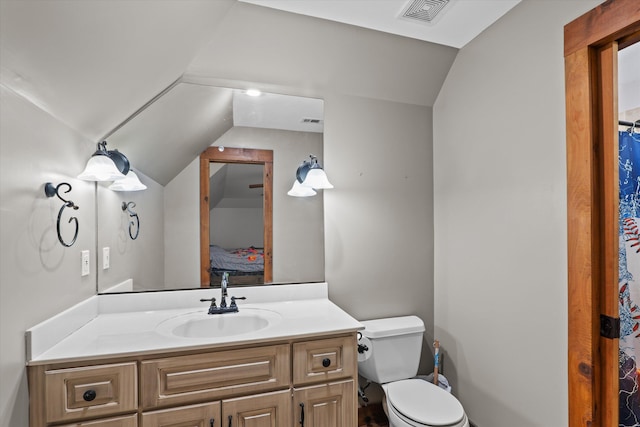 bathroom with vanity, toilet, and lofted ceiling