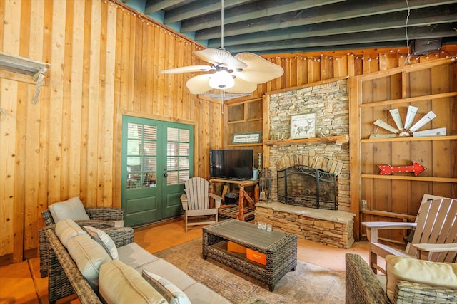 living room with beamed ceiling, ceiling fan, and a stone fireplace