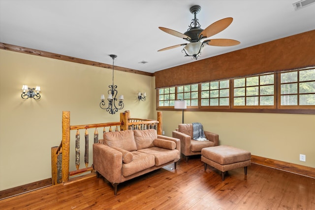 living room featuring hardwood / wood-style floors, ceiling fan with notable chandelier, and ornamental molding