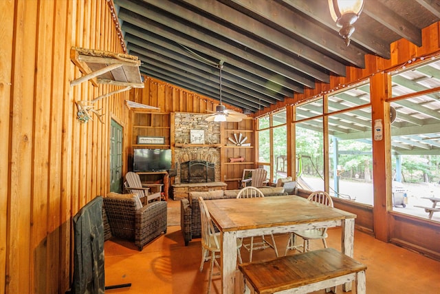 dining area featuring a fireplace, high vaulted ceiling, ceiling fan, and wooden walls