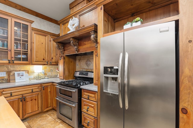 kitchen with light stone countertops, light tile patterned floors, backsplash, and stainless steel appliances