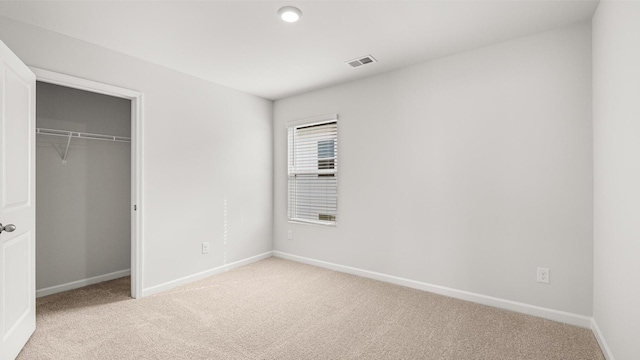 unfurnished bedroom with light carpet and a closet