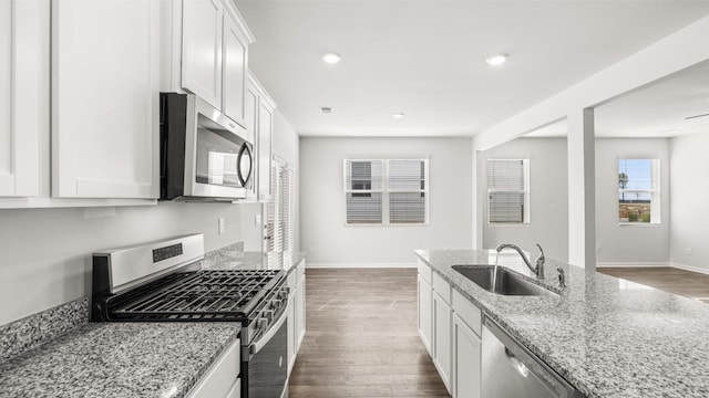 kitchen with stainless steel appliances, sink, white cabinets, and light stone counters