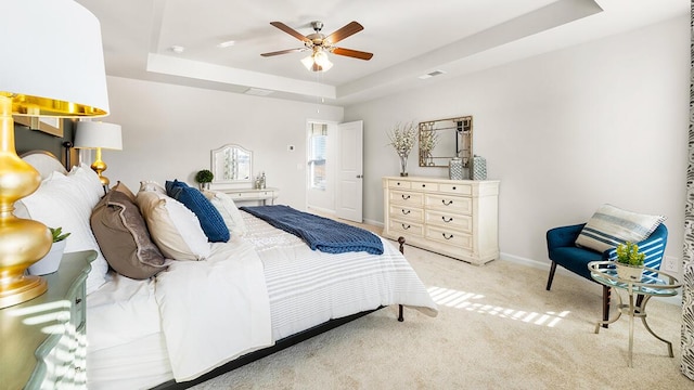 bedroom with ceiling fan, light colored carpet, and a raised ceiling