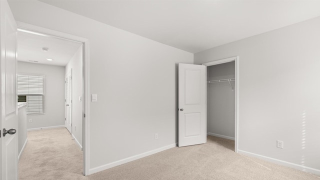 unfurnished bedroom with light carpet and a closet