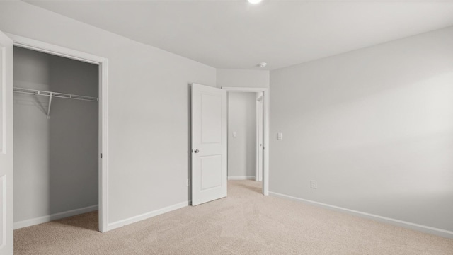 unfurnished bedroom featuring light colored carpet and a closet