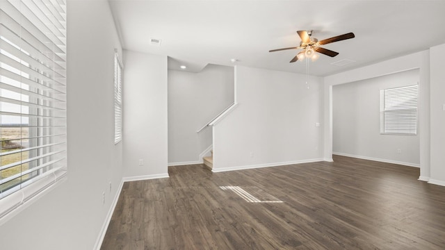 unfurnished living room with plenty of natural light, dark wood-type flooring, and ceiling fan