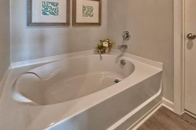 bathroom with hardwood / wood-style flooring and a bath