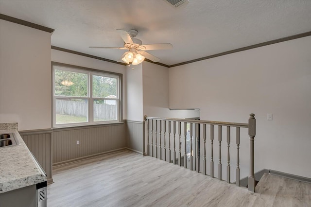 interior space with ceiling fan, sink, crown molding, hardwood / wood-style floors, and a textured ceiling