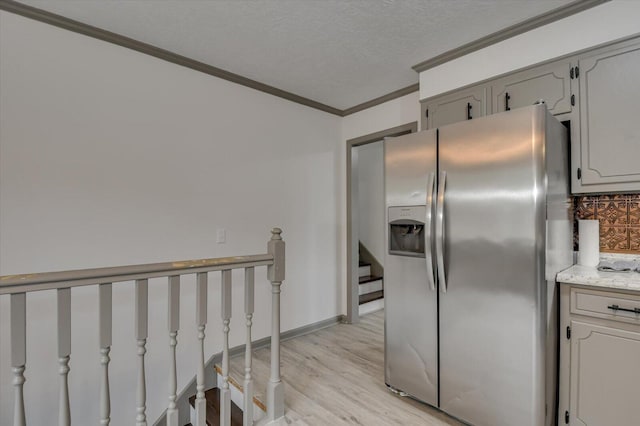 kitchen with crown molding, stainless steel refrigerator with ice dispenser, decorative backsplash, a textured ceiling, and light hardwood / wood-style floors