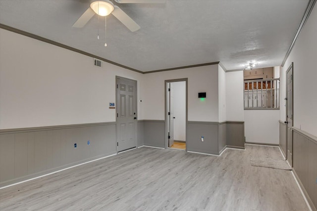 spare room with a textured ceiling, light hardwood / wood-style flooring, ceiling fan, and crown molding