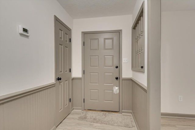 doorway featuring a textured ceiling and light hardwood / wood-style flooring