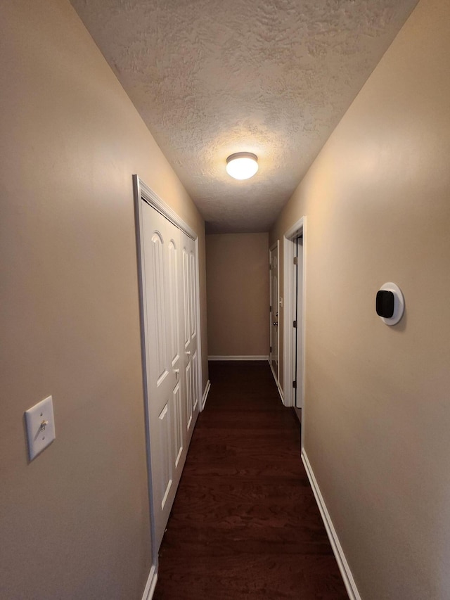 corridor featuring dark wood-type flooring and a textured ceiling