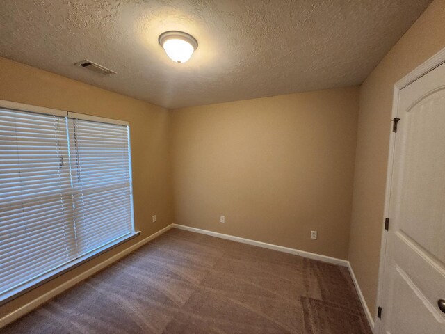 carpeted empty room featuring a textured ceiling