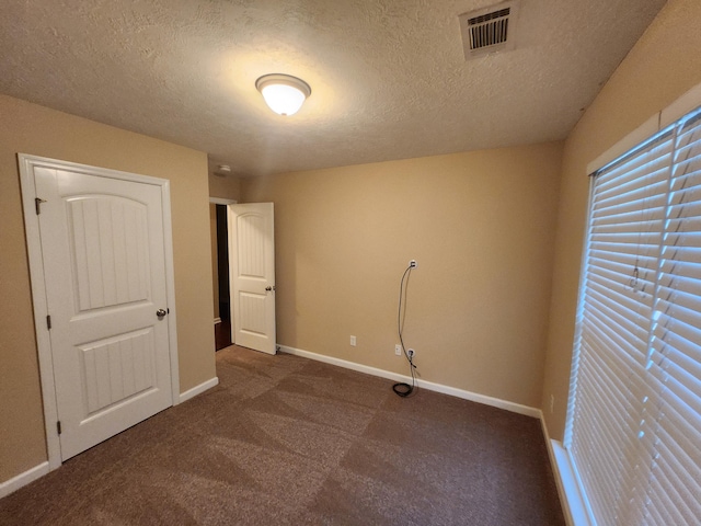 spare room with dark carpet and a textured ceiling