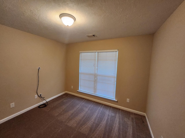 empty room featuring a textured ceiling and dark colored carpet