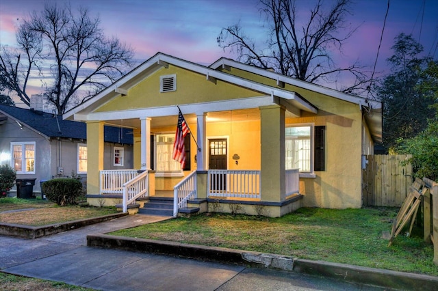 view of front facade with covered porch and a lawn