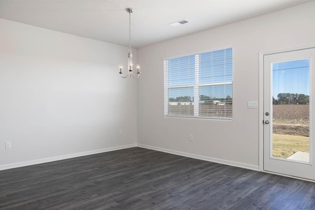 spare room with dark wood-type flooring and a notable chandelier