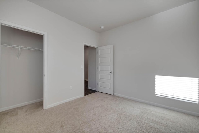 unfurnished bedroom with light colored carpet and a closet