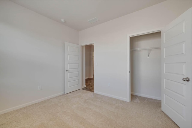 unfurnished bedroom featuring light carpet and a closet