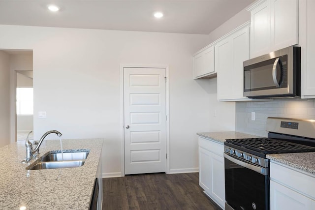 kitchen featuring white cabinets, appliances with stainless steel finishes, light stone countertops, and sink